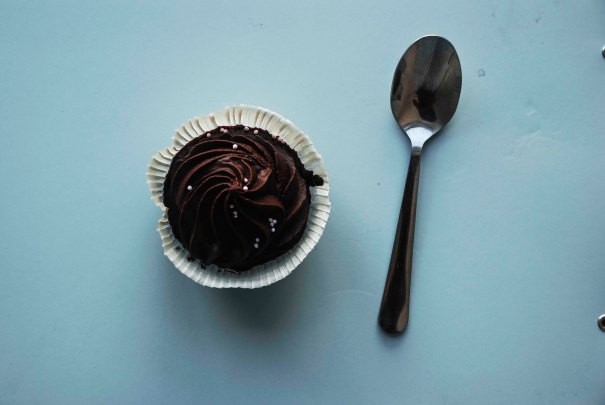 A single chocolate cupcake, on a blue background